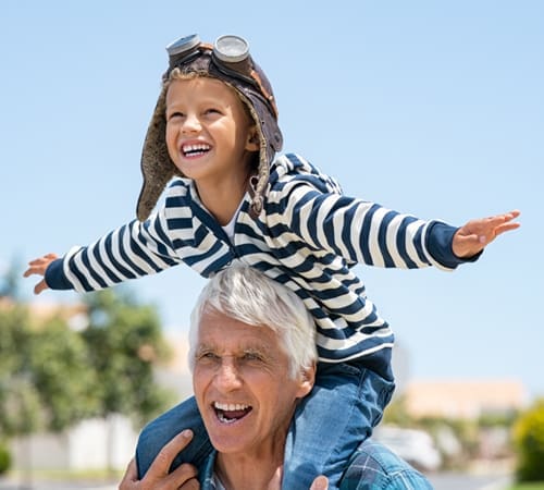 Little boy pretending to be an airplane and sitting on grandpa's shoulders